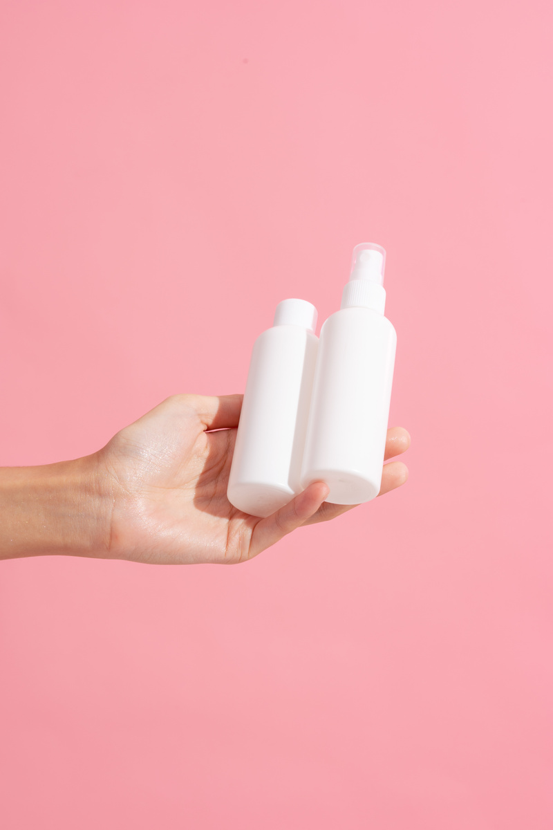 Person's Hand with Cosmetic Bottles