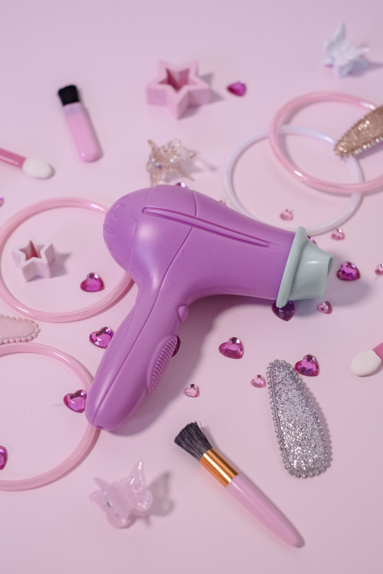 Hair Dryer, Accessories and Trinkets on Pink Background